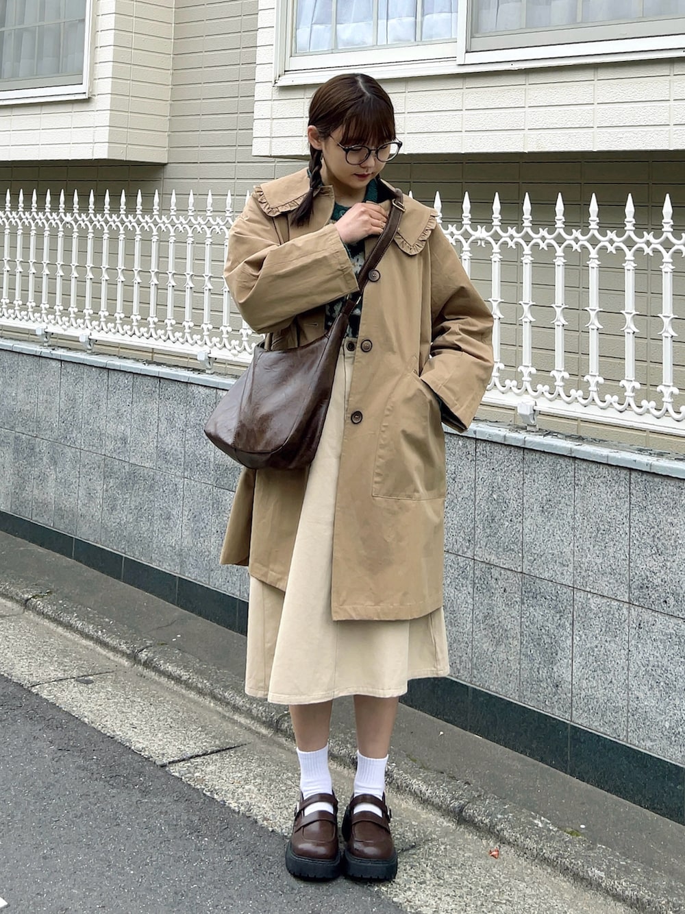 グリーン系のカーディガン/ボレロ、ブラウン系のショルダーバッグ、ホワイト系のスカートを着用したレディースの春コーディネートの2枚目の写真