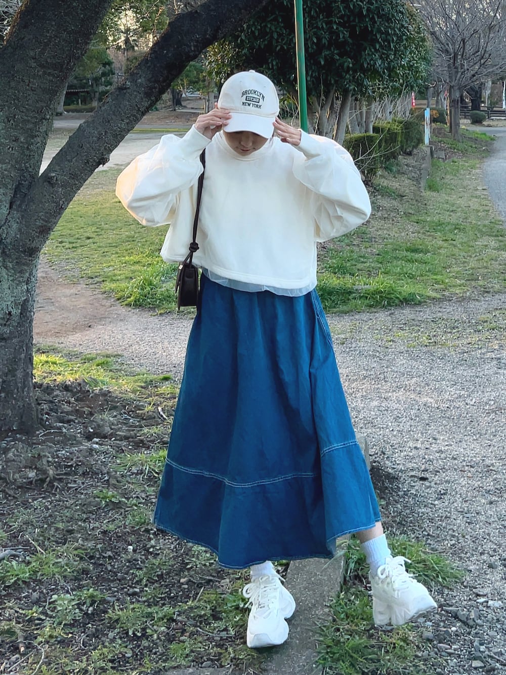 ホワイト系のスウェット、ブルー系のデニムスカート、ホワイト系のスニーカーを着用したレディースの春コーディネートの3枚目の写真
