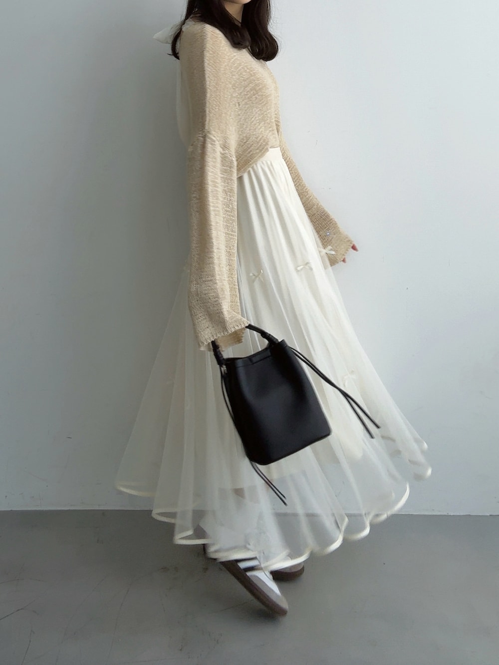 ベージュ系のニット/セーター、ホワイト系のスカート、ブラック系のハンドバッグを着用したレディースの秋コーディネートの3枚目の写真