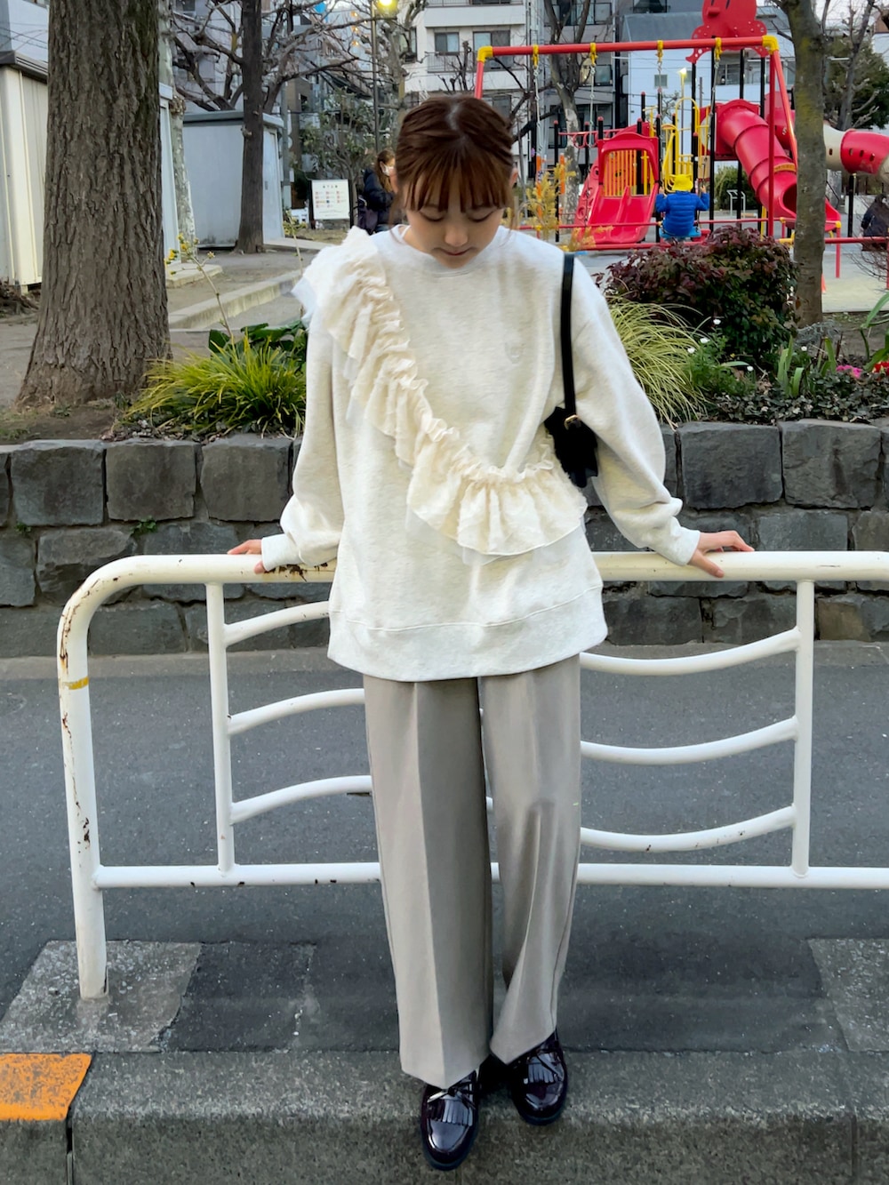 ベージュ系のスウェット、ブラック系のハンドバッグ、グレー系のパンツを着用したレディースの春コーディネートの2枚目の写真