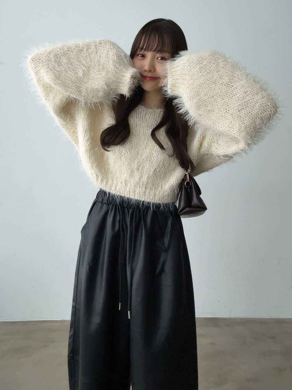 ベージュ系のニット/セーター、ブラック系のその他パンツ、ブラウン系のショルダーバッグを着用したレディースの秋コーディネートの2枚目の写真