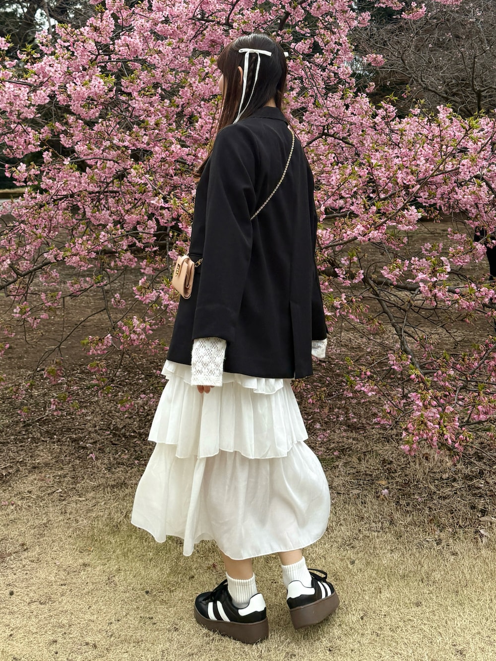 ブラック系のノーカラージャケット、ホワイト系のスカート、ホワイト系のTシャツ/カットソーを着用したレディースの春コーディネートの2枚目の写真