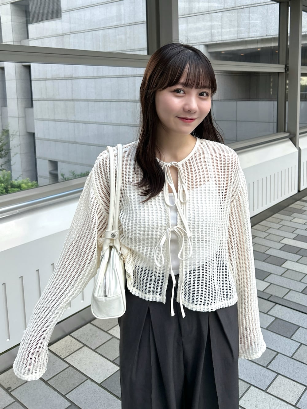 ベージュ系のカーディガン/ボレロ、グレー系のスラックス、ホワイト系のバッグを着用したレディースの秋コーディネートの4枚目の写真