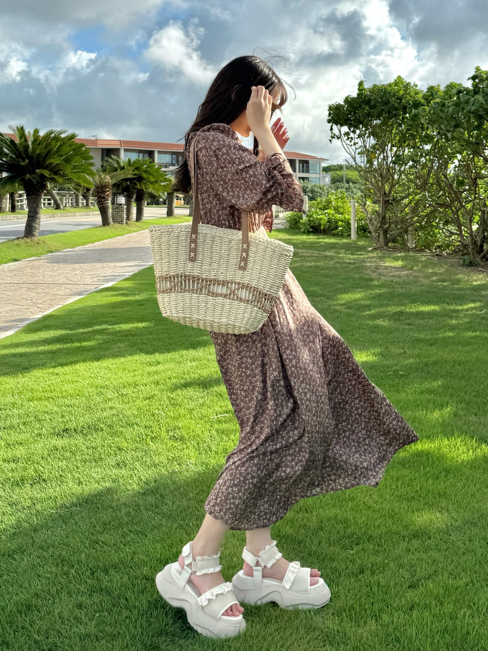 ブラウン系のワンピース、ホワイト系のサンダル、ホワイト系のかごバッグを着用したレディースの夏コーディネートの2枚目の写真