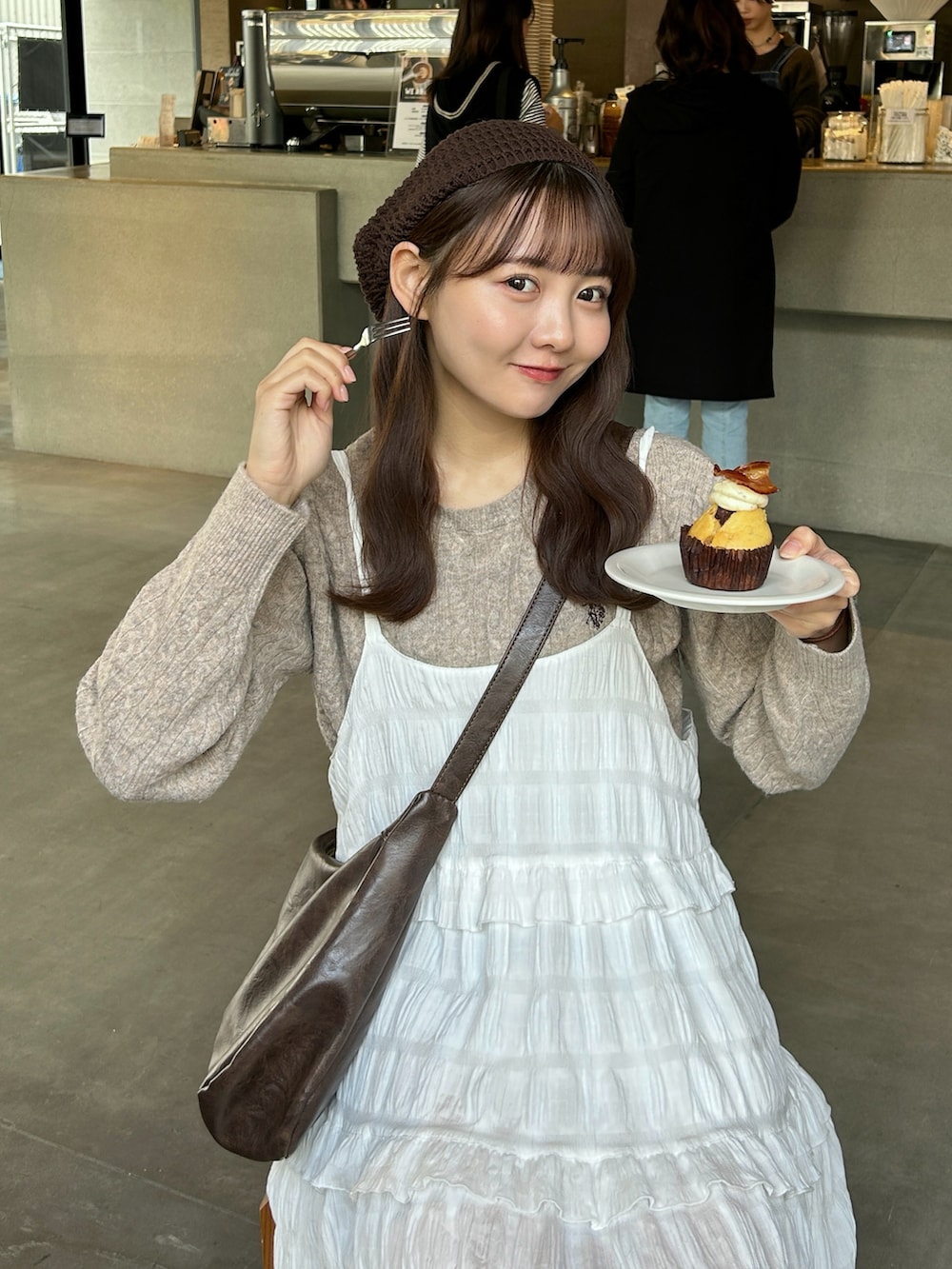 ホワイト系のワンピース、ベージュ系のニット/セーター、ブラウン系のショルダーバッグを着用したレディースの秋コーディネートの2枚目の写真
