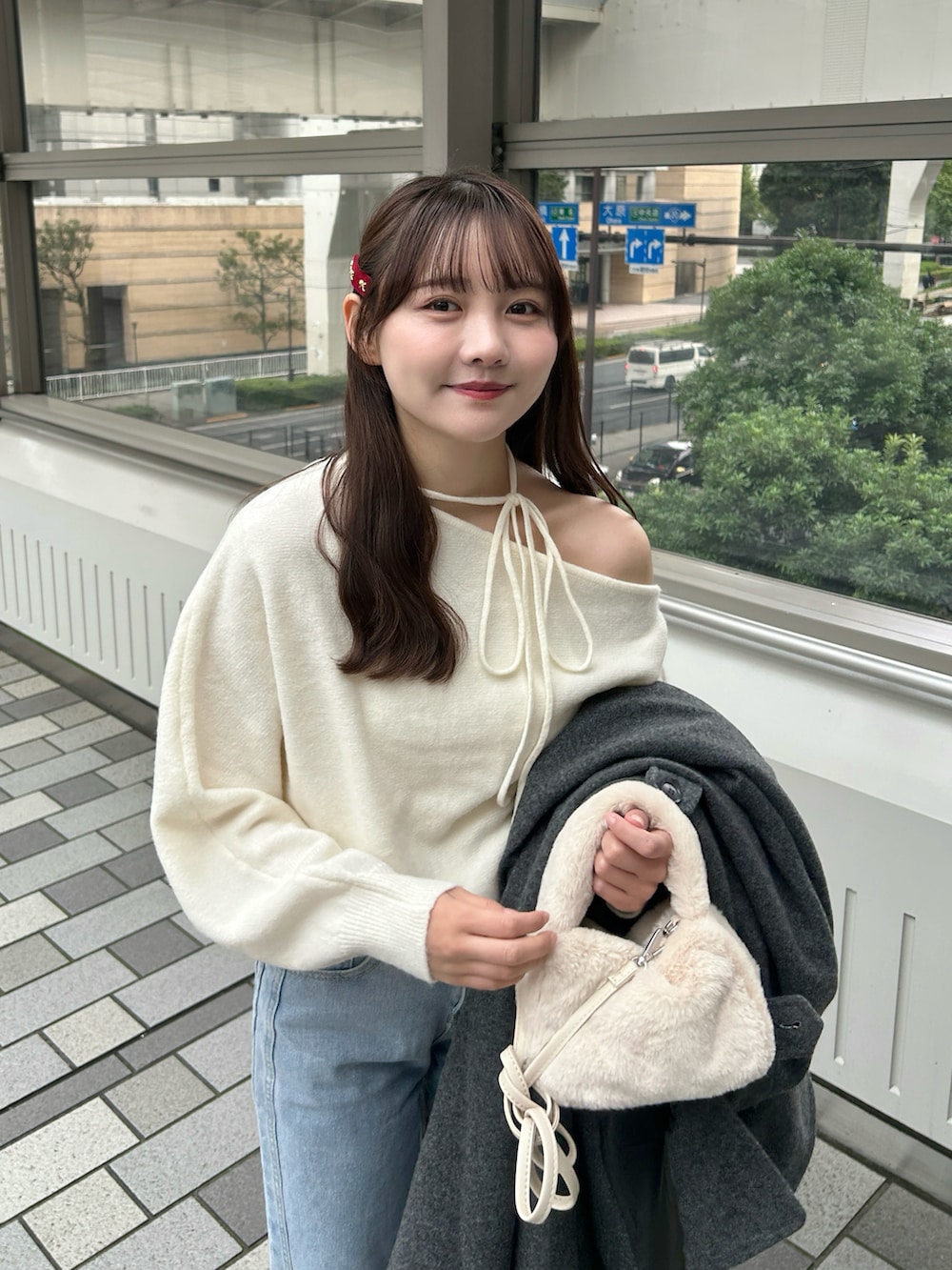 ブラック系のステンカラーコート、ホワイト系のハンドバッグ、ブルー系のデニムパンツを着用したレディースの冬コーディネートの4枚目の写真