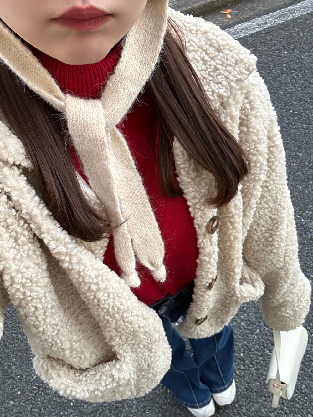 レッド系のニット/セーター、ホワイト系のブルゾン、ブルー系のデニムパンツを着用したレディースの冬コーディネートの2枚目の写真
