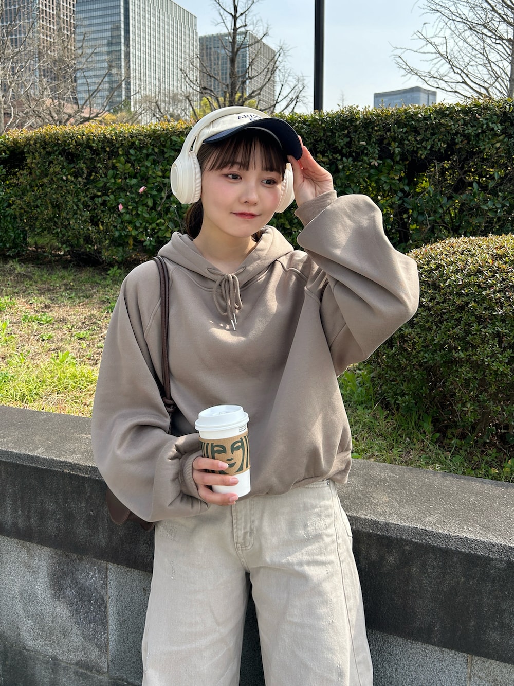 ベージュ系のデニムパンツ、ベージュ系のスニーカー、ブラウン系のハンドバッグを着用したレディースの春コーディネートの3枚目の写真