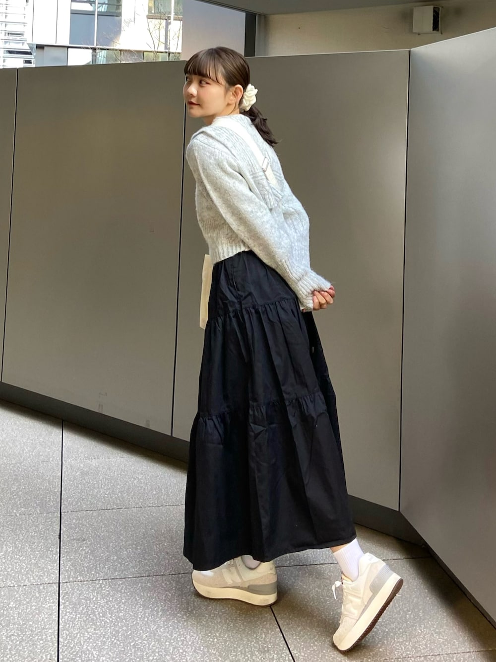 ブラック系のワンピース、グレー系のニット/セーター、ベージュ系のショルダーバッグを着用したレディースの春コーディネートの5枚目の写真