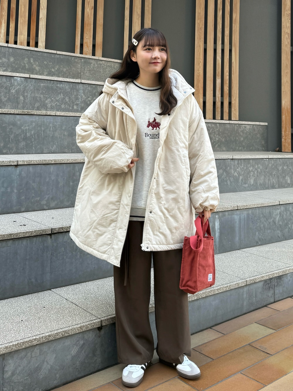 レッド系のショルダーバッグ、ベージュ系のスウェット、ブラウン系のその他パンツを着用したレディースの冬コーディネートの4枚目の写真