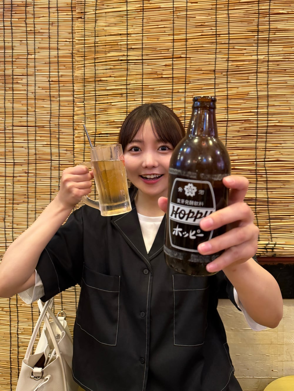 ブラック系のセットアップ、ホワイト系のハンドバッグ、ホワイト系のパンプスを着用したレディースの夏コーディネートの3枚目の写真