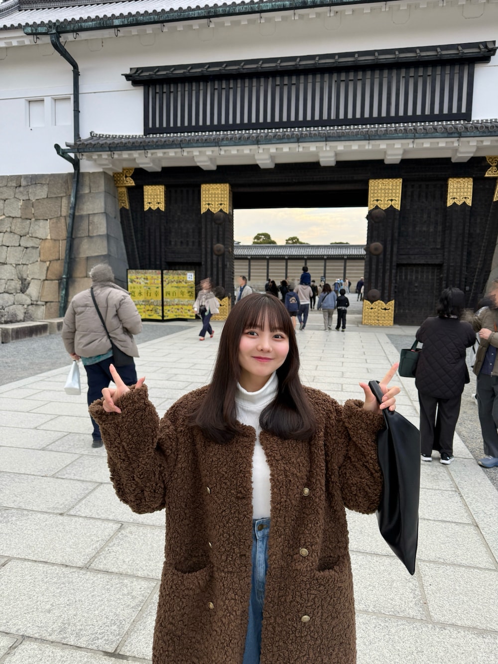 ブルー系のデニムパンツ、ブラック系のハンドバッグ、ブラウン系のサンダルを着用したレディースの冬コーディネートの4枚目の写真