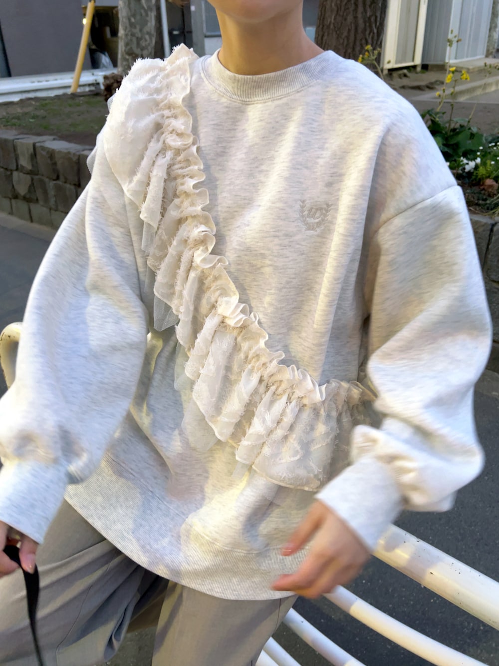 ベージュ系のスウェット、ブラック系のハンドバッグ、グレー系のパンツを着用したレディースの春コーディネートの3枚目の写真