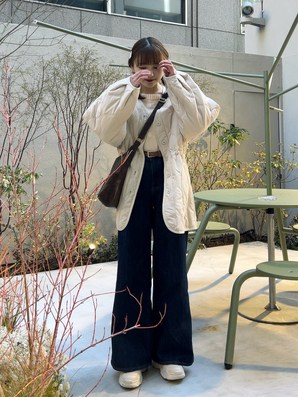 ホワイト系のノーカラージャケット、ブルー系のデニムパンツ、ホワイト系のスニーカーを着用したレディースの春コーディネートの3枚目の写真