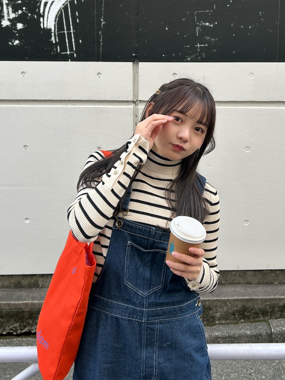 ブルー系のサロペット/オーバーオール、ホワイト系のニット/セーター、オレンジ系のトートバッグを着用したレディースの春コーディネートの4枚目の写真