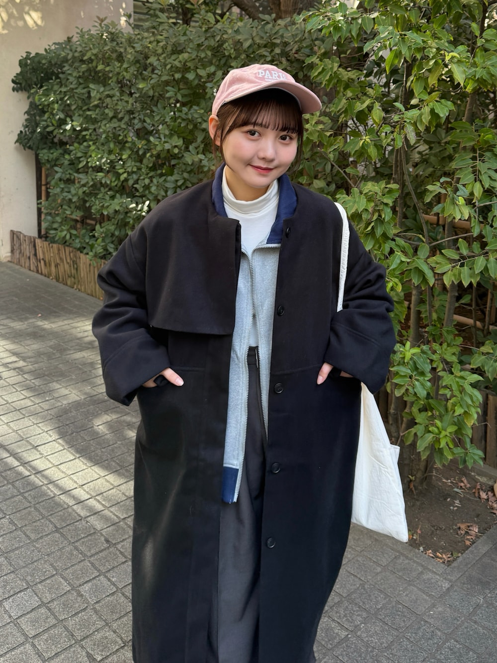 グレー系のブルゾン、ホワイト系のトップス、グレー系のスラックスを着用したレディースの冬コーディネートの3枚目の写真