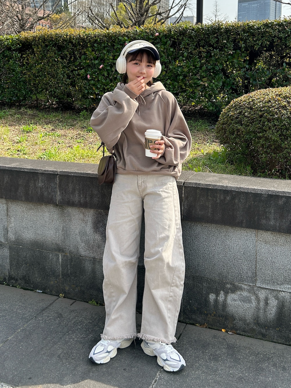 ベージュ系のデニムパンツ、ベージュ系のスニーカー、ブラウン系のハンドバッグを着用したレディースの春コーディネートの5枚目の写真