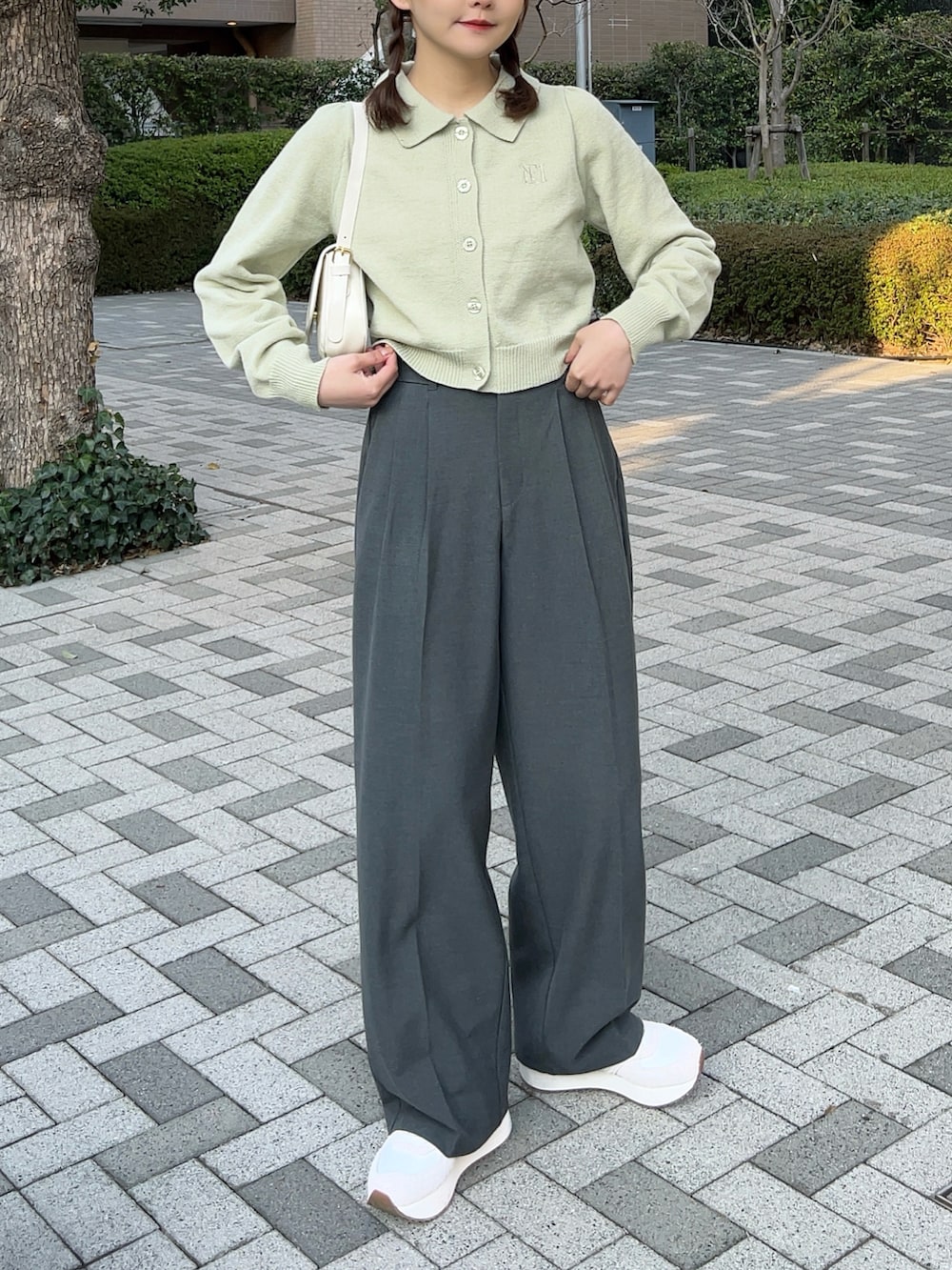 グリーン系のニット/セーター、ホワイト系のハンドバッグ、グレー系のパンツを着用したレディースの春コーディネートの2枚目の写真