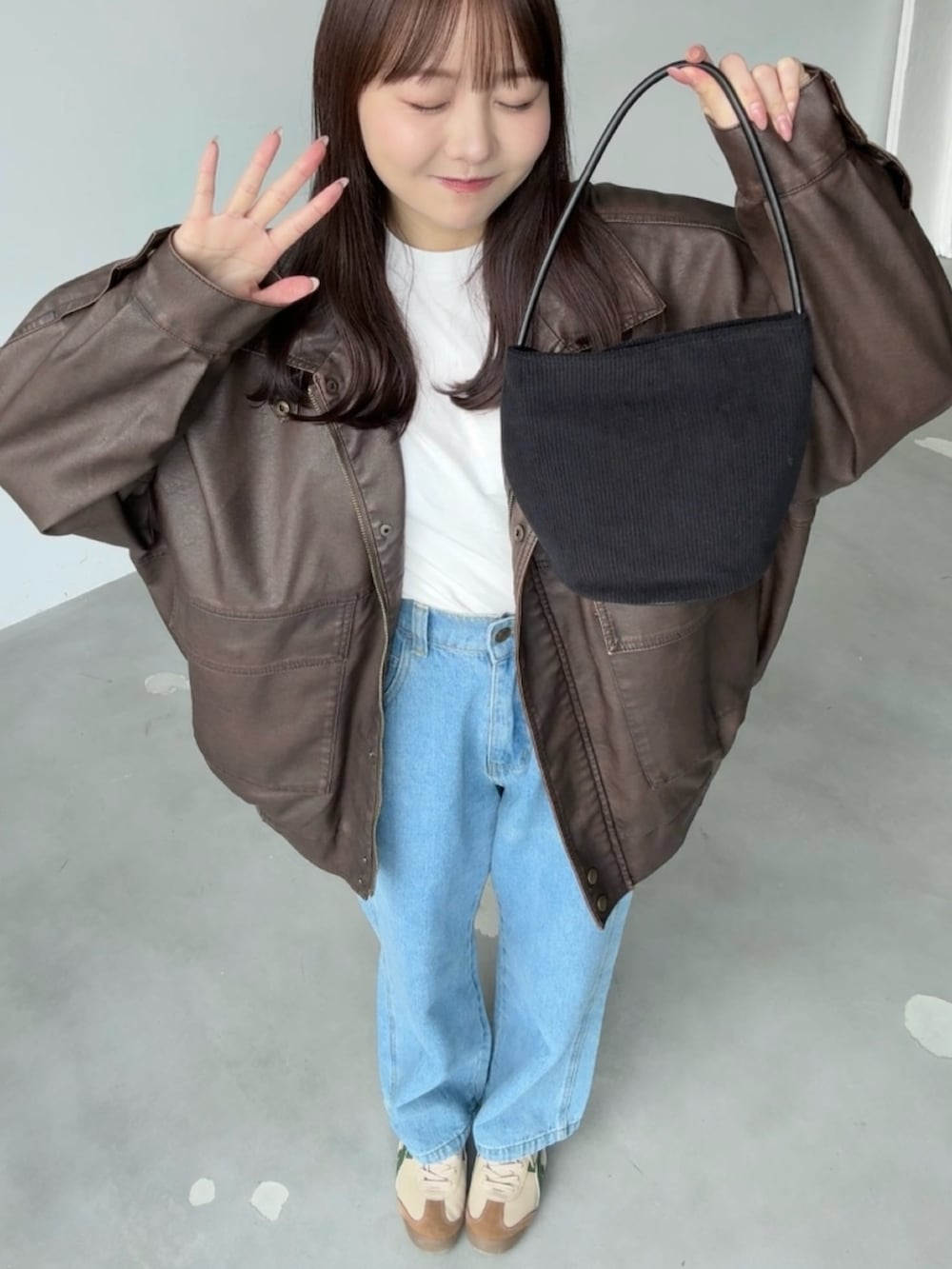 ブラック系のショルダーバッグ、ブラウン系のブルゾン、ホワイト系のTシャツ/カットソーを着用したレディースの春コーディネートの2枚目の写真