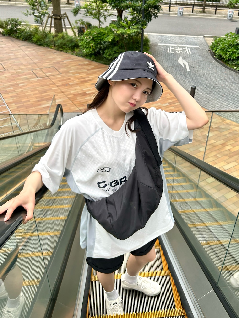 ブラック系のショルダーバッグ、ホワイト系のTシャツ/カットソー、ブラック系のデニムパンツを着用したレディースの夏コーディネートの3枚目の写真