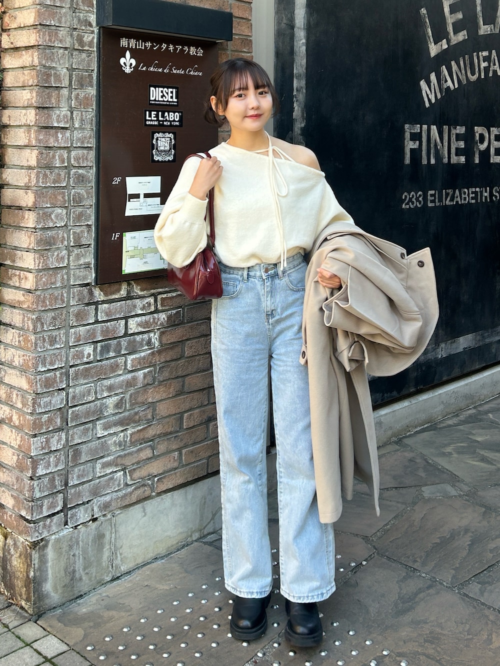 ホワイト系のニット/セーター、ベージュ系のステンカラーコート、ブルー系のデニムパンツを着用したレディースの冬コーディネートの4枚目の写真