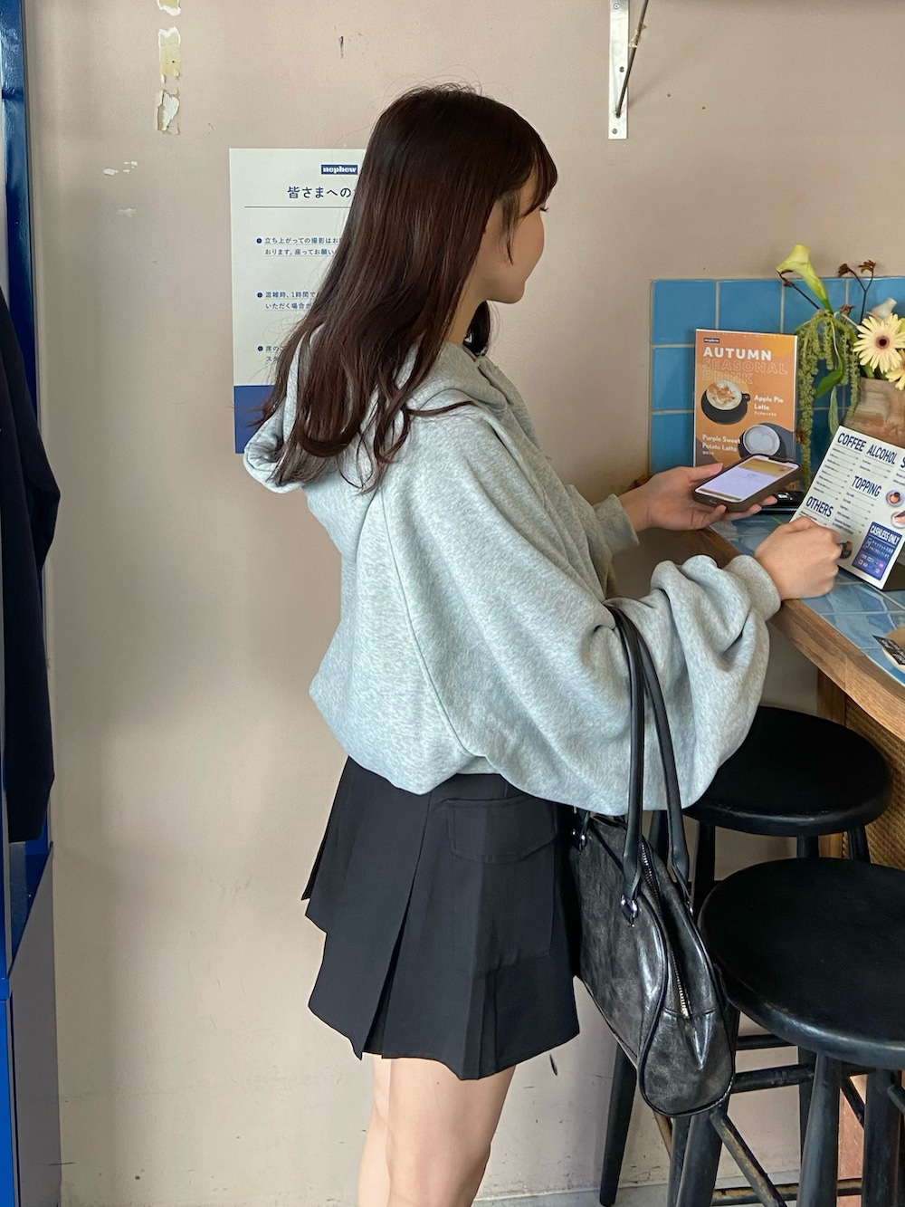 グレー系のパーカー、ブラック系のブルゾン、ブラック系のスカートを着用したレディースの秋コーディネートの4枚目の写真