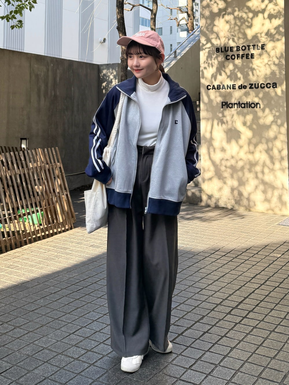 グレー系のブルゾン、ホワイト系のトップス、グレー系のスラックスを着用したレディースの冬コーディネートの4枚目の写真