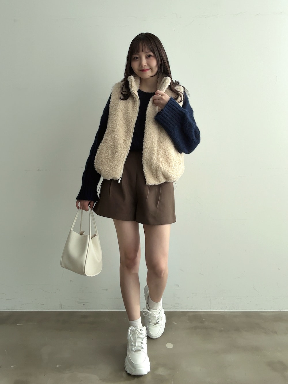 ホワイト系のスニーカー、ブルー系のニット/セーター、ホワイト系のその他アウターを着用したレディースの冬コーディネートの4枚目の写真
