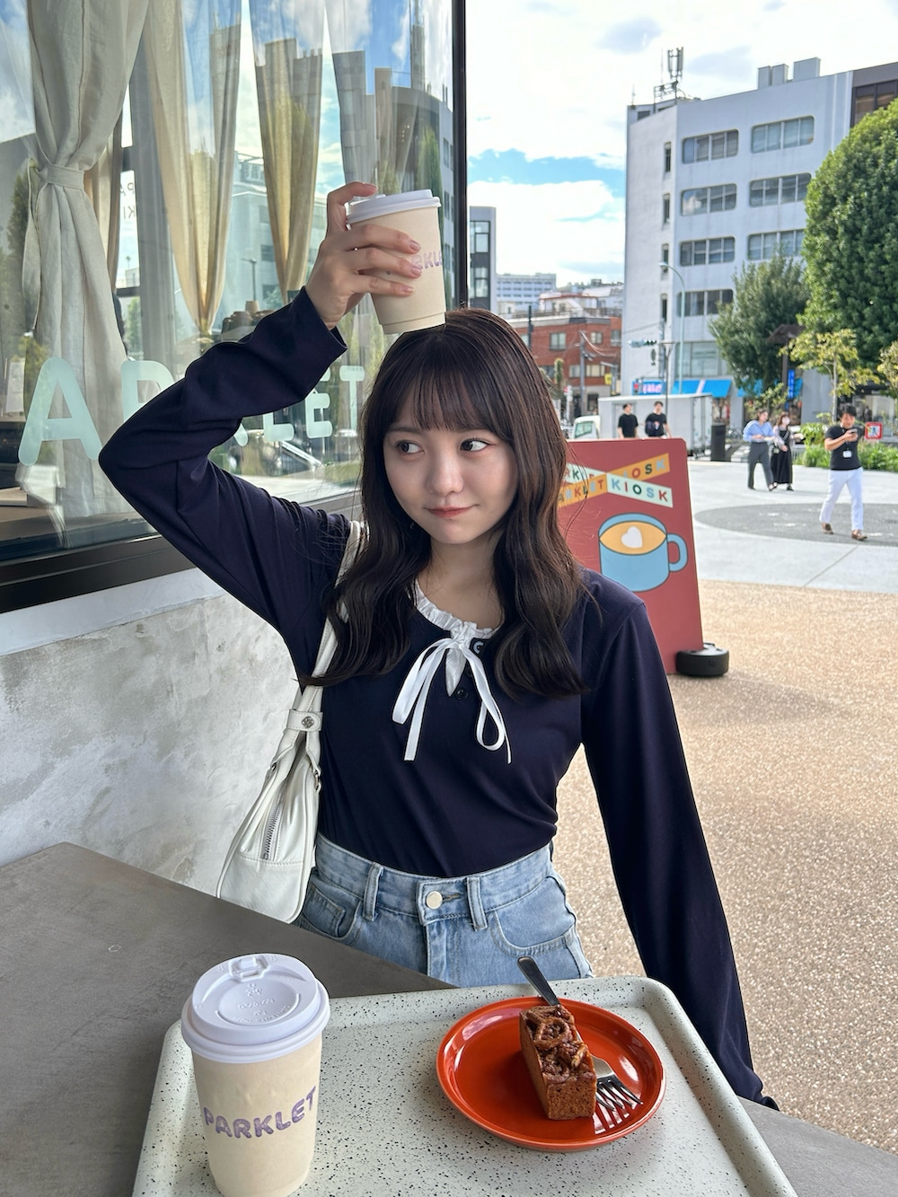 ホワイト系のバッグ、ブルー系のデニムパンツ、ホワイト系のスニーカーを着用したレディースの秋コーディネートの3枚目の写真