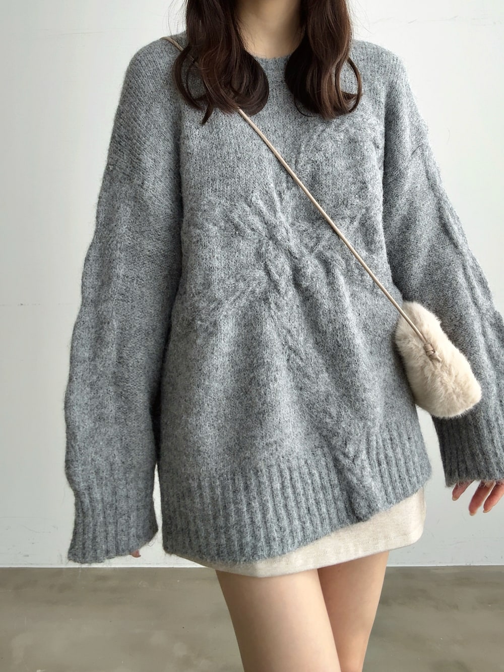 グレー系のニット/セーター、ホワイト系のスカート、ホワイト系のショルダーバッグを着用したレディースの冬コーディネートの4枚目の写真