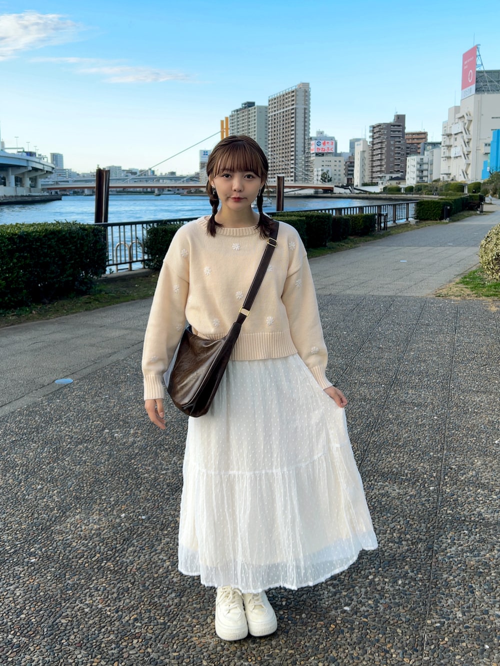 ピンク系のニット/セーター、ブラウン系のショルダーバッグ、ホワイト系のスカートを着用したレディースの冬コーディネートの5枚目の写真