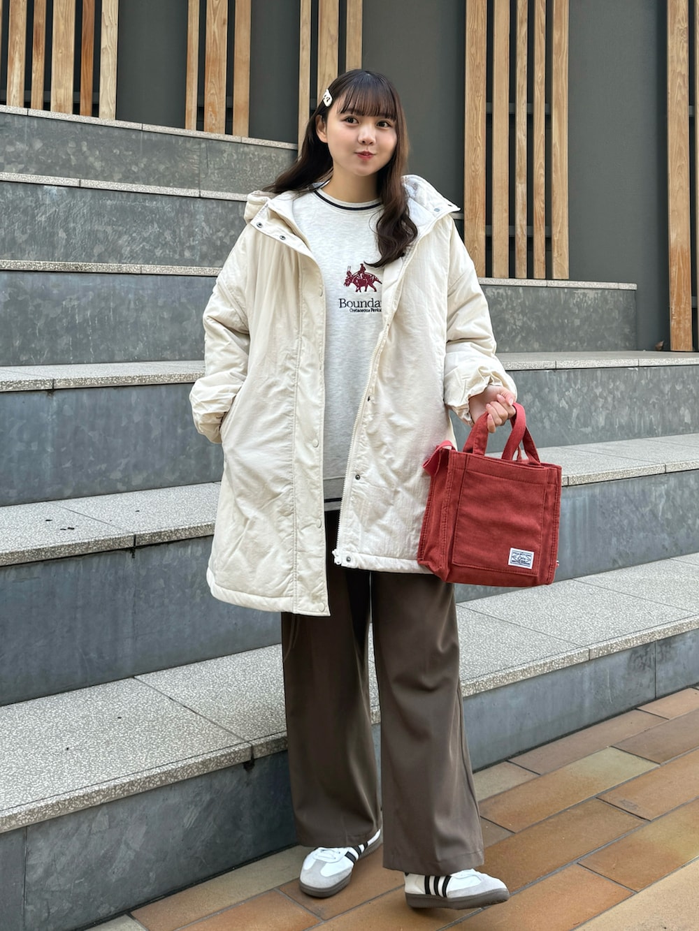 ホワイト系のナイロンジャケット、ベージュ系のスウェット、レッド系のショルダーバッグを着用したレディースの冬コーディネートの4枚目の写真