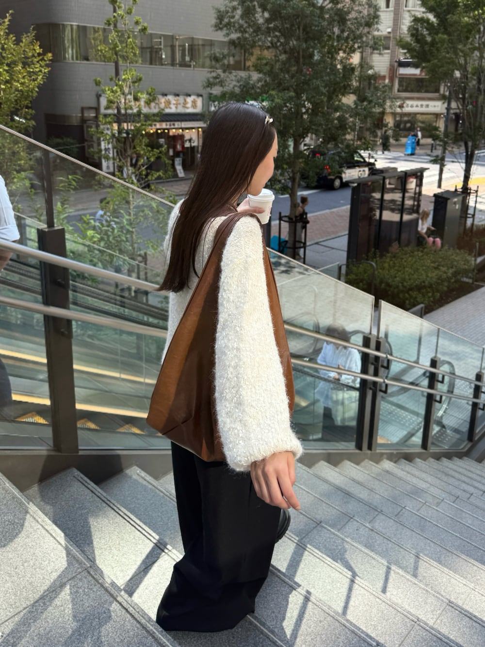 ベージュ系のニット/セーター、イエロー系のトートバッグ、ブラウン系のタンクトップを着用したレディースの秋コーディネートの3枚目の写真