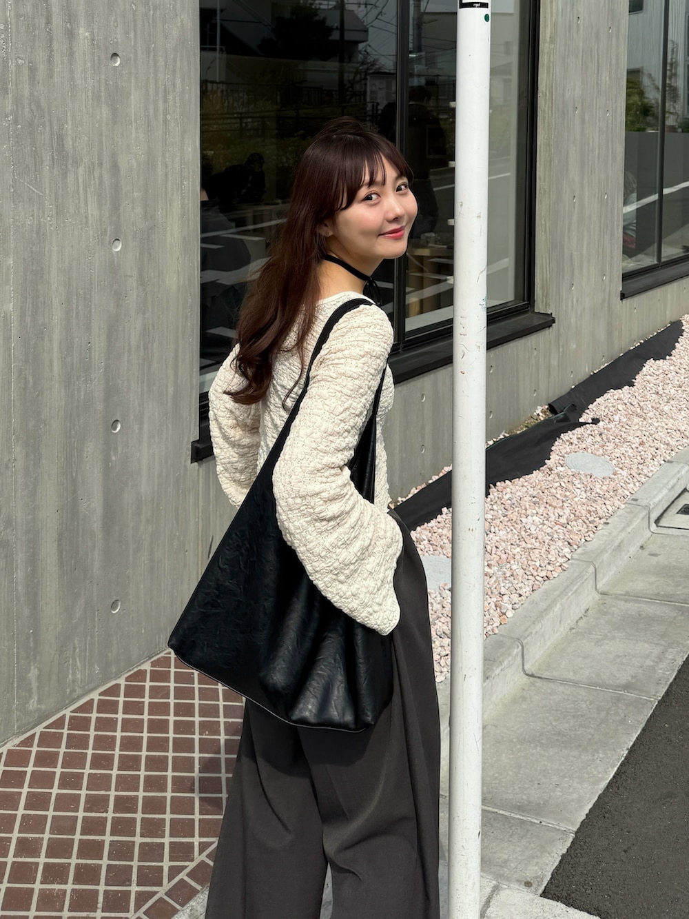 ブラック系のバッグ、ホワイト系のTシャツ/カットソー、グレー系のスラックスを着用したレディースの春コーディネートの4枚目の写真