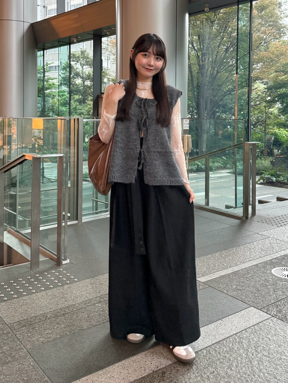 グレー系のベスト、ブラック系のその他パンツ、ホワイト系のスニーカーを着用したレディースの秋コーディネートの3枚目の写真