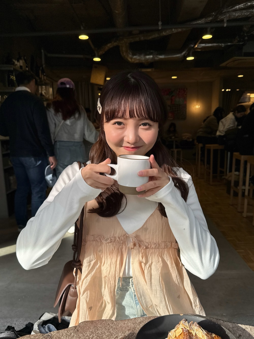 ピンク系のキャミソール、ホワイト系のトップス、ブルー系のデニムパンツを着用したレディースの春コーディネートの3枚目の写真