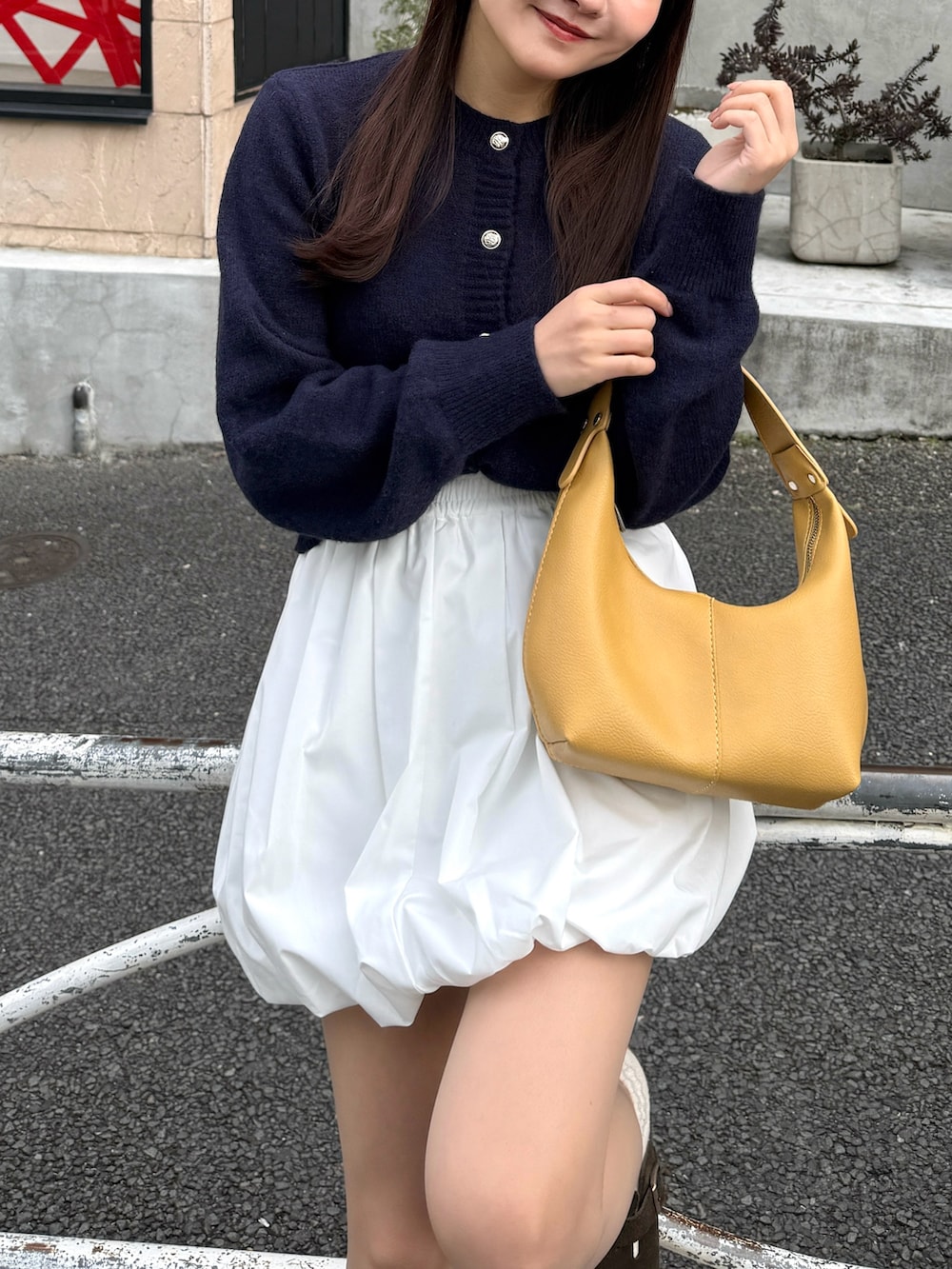 ベージュ系のスカート、ブラウン系のサンダル、イエロー系のハンドバッグを着用したレディースの春コーディネートの2枚目の写真