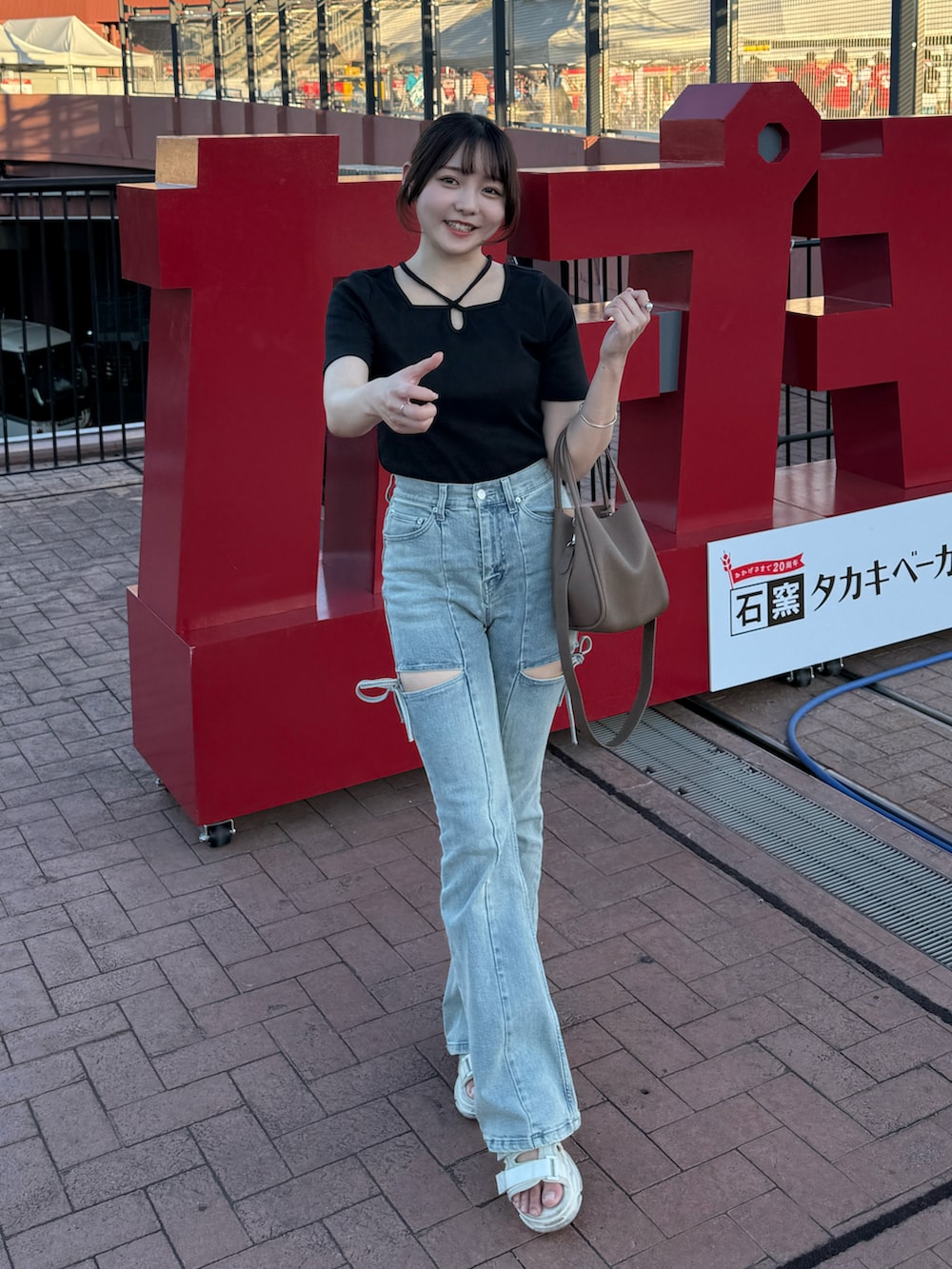 ブラック系のTシャツ/カットソー、ホワイト系のサンダル、ブルー系のデニムパンツを着用したレディースの夏コーディネートの2枚目の写真