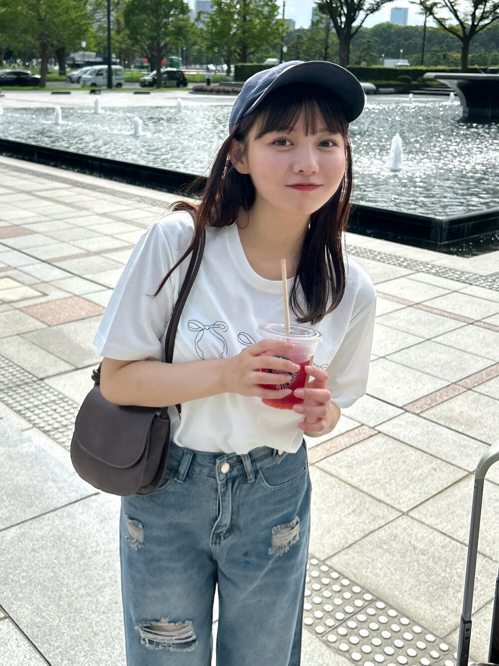 ブルー系のデニムパンツ、ブラウン系のバッグ、ホワイト系のTシャツ/カットソーを着用したレディースの秋コーディネートの4枚目の写真