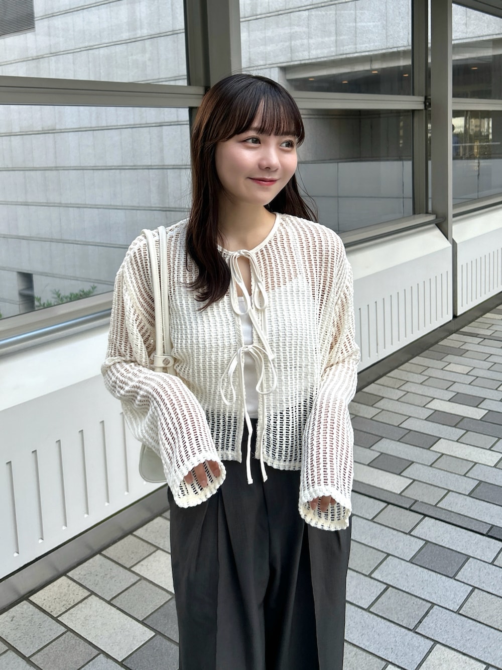ベージュ系のカーディガン/ボレロ、ホワイト系のバッグ、グレー系のスラックスを着用したレディースの春コーディネートの3枚目の写真