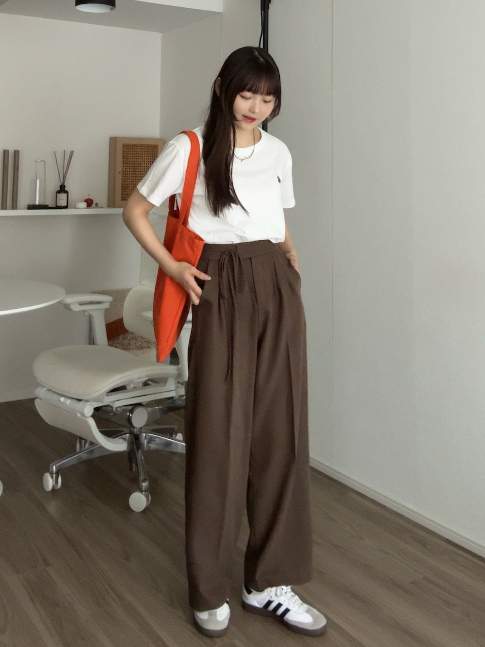 ホワイト系のTシャツ/カットソー、ブラウン系のその他パンツ、オレンジ系のトートバッグを着用したレディースの秋コーディネートの2枚目の写真