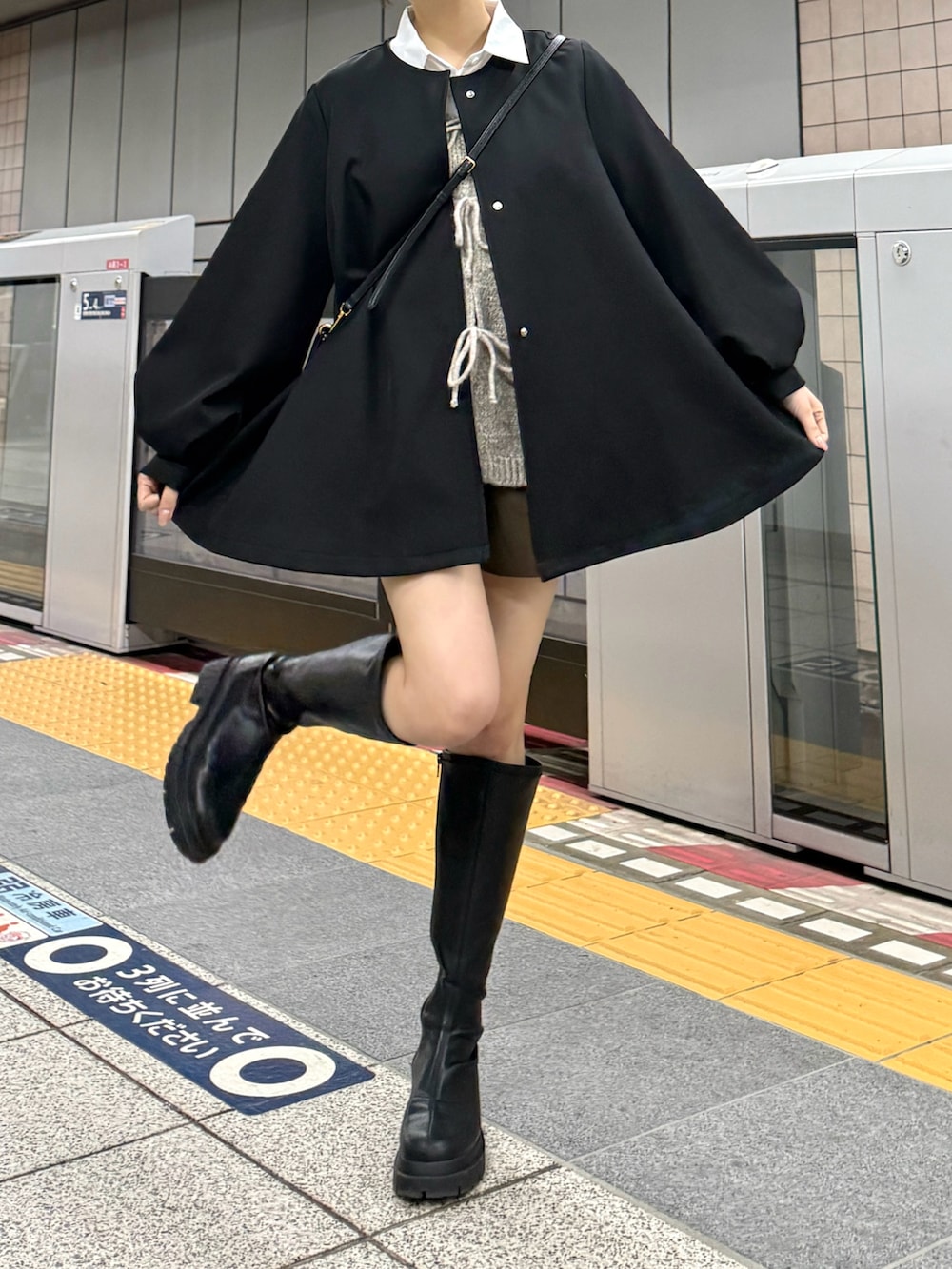 ブラック系のノーカラージャケット、ブラック系のブーツ、ホワイト系のシャツ/ブラウスを着用したレディースの春コーディネートの2枚目の写真