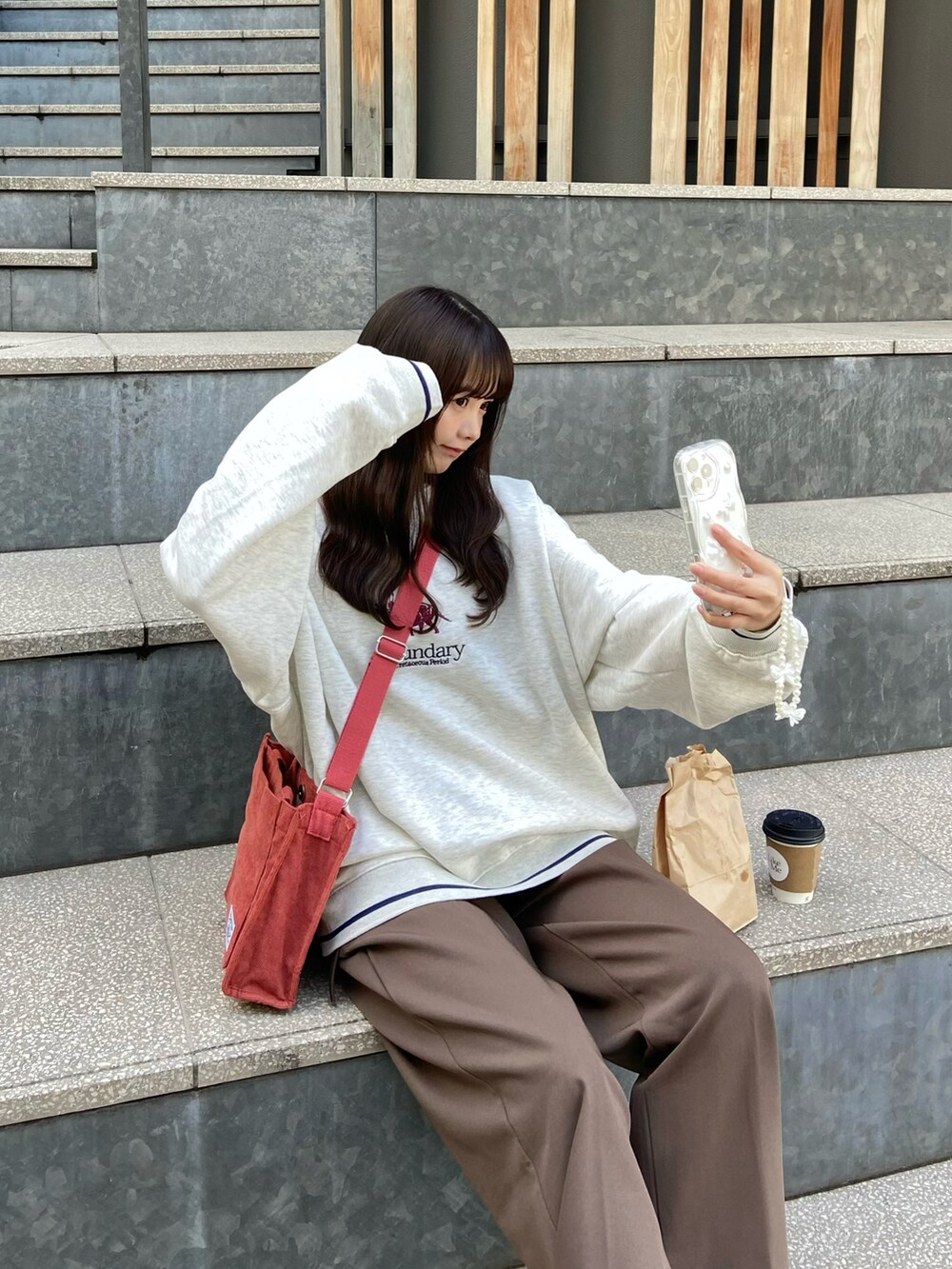 ホワイト系のナイロンジャケット、ベージュ系のスウェット、レッド系のショルダーバッグを着用したレディースの冬コーディネートの2枚目の写真