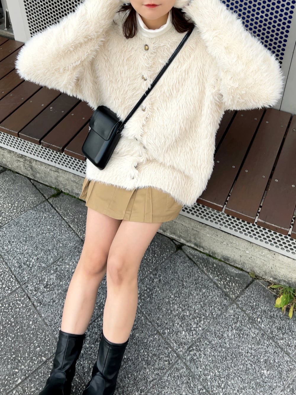 ブラック系のブーツ、ベージュ系のスカート、ブラック系のショルダーバッグを着用したレディースの冬コーディネートの5枚目の写真