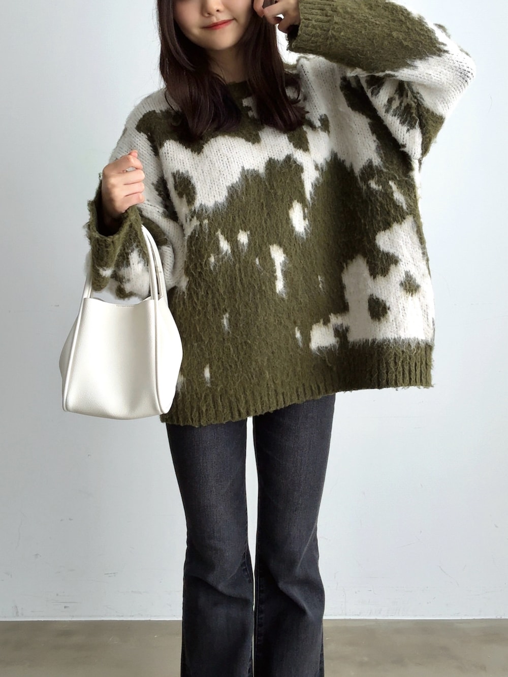 グリーン系のニット/セーター、ブラック系のデニムパンツ、ホワイト系のハンドバッグを着用したレディースの冬コーディネートの3枚目の写真