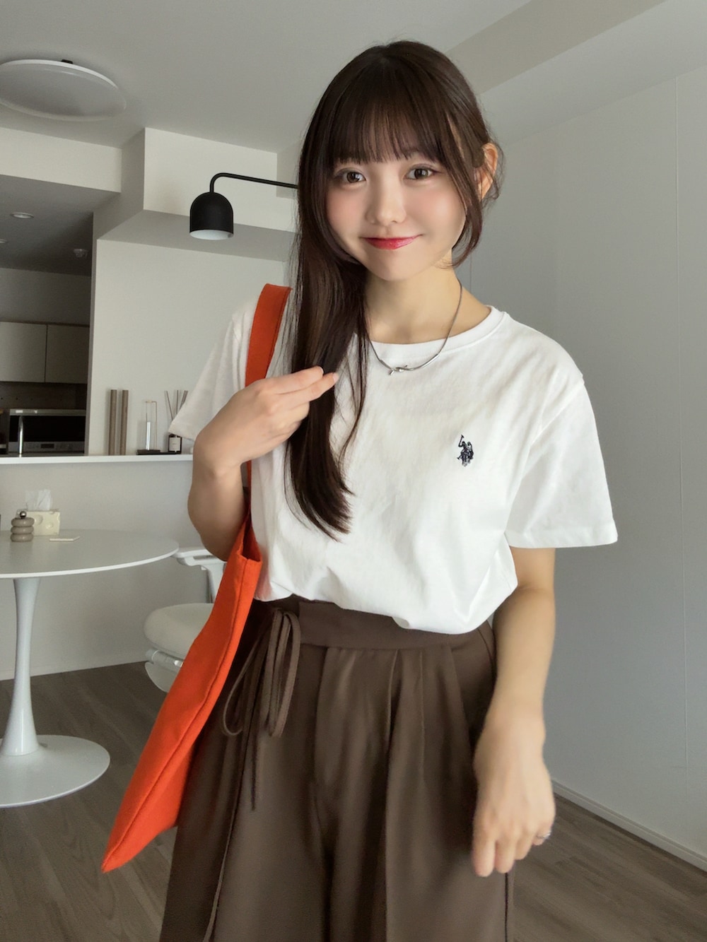 ホワイト系のTシャツ/カットソー、ブラウン系のその他パンツ、オレンジ系のトートバッグを着用したレディースの秋コーディネートの3枚目の写真