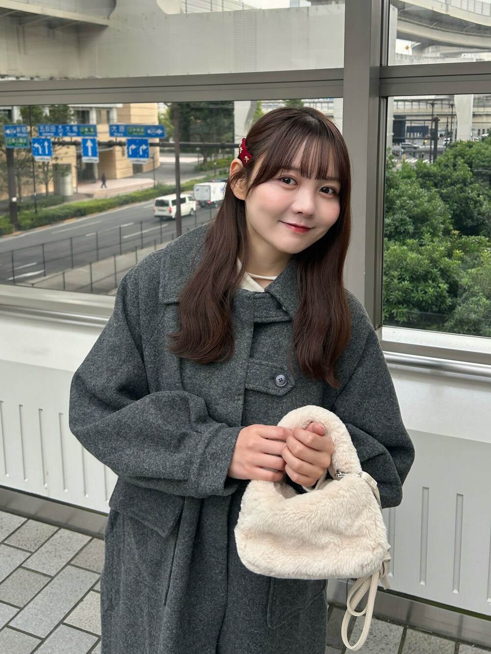 ブラック系のステンカラーコート、ホワイト系のハンドバッグ、ブルー系のデニムパンツを着用したレディースの冬コーディネートの2枚目の写真