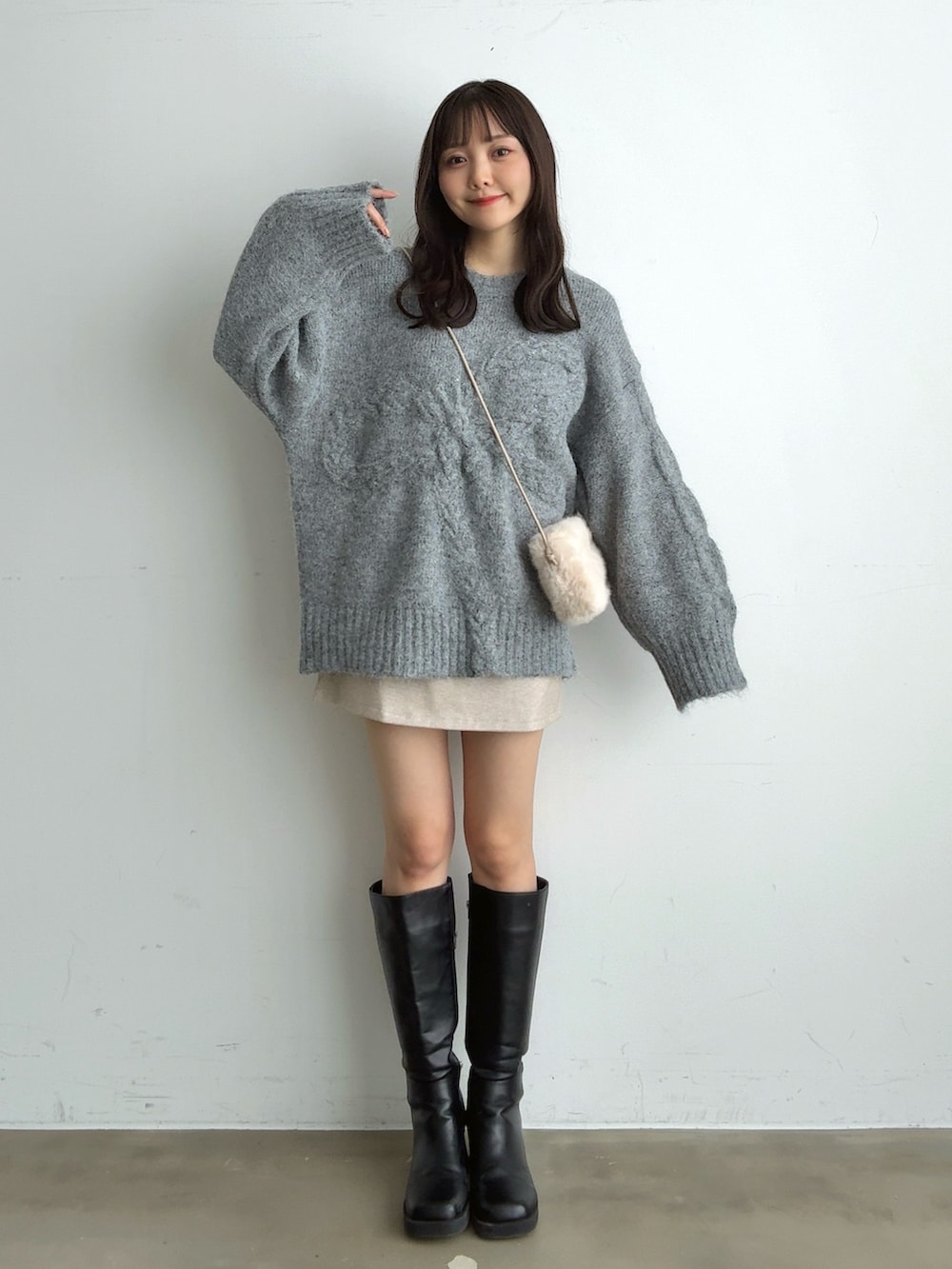 グレー系のニット/セーター、ホワイト系のスカート、ホワイト系のショルダーバッグを着用したレディースの冬コーディネートの3枚目の写真