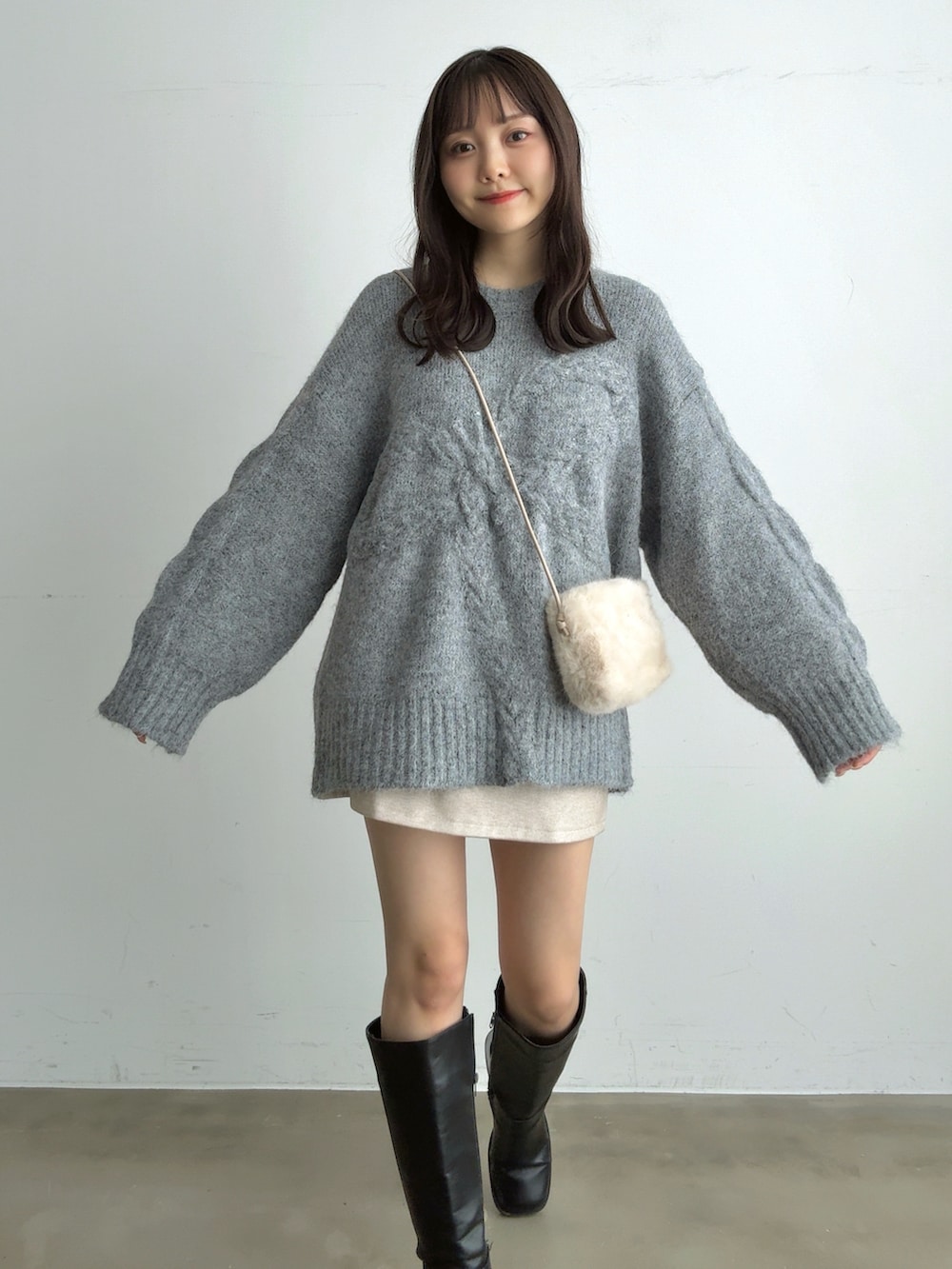 グレー系のニット/セーター、ホワイト系のスカート、ホワイト系のショルダーバッグを着用したレディースの冬コーディネートの2枚目の写真