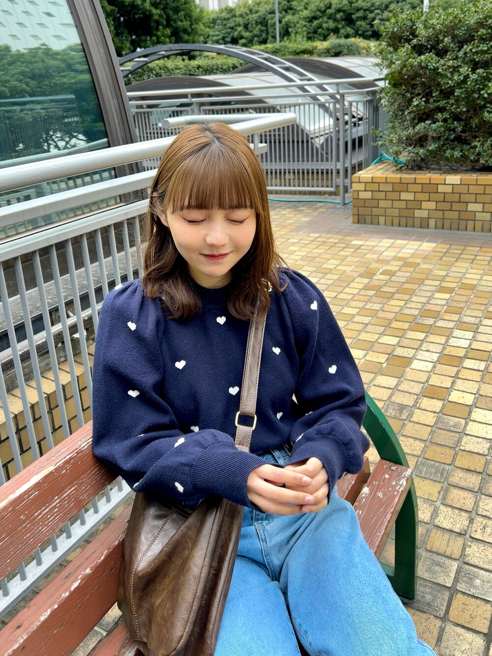 ブルー系のニット/セーター、ブラウン系のショルダーバッグ、ブルー系のデニムパンツを着用したレディースの春コーディネートの4枚目の写真